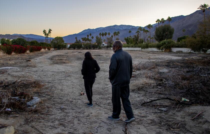 PALM SPRINGS, CA - DECEMBER 13, 2022: Joe Abner with his wife Vera on their daily walk through a vacant lot which was once a part of Section 14 where he grew up on December 13, 2022 in Palm Springs, California. Abner was 13 when his family fled Section 14 in Palm Springs, leaving the home his father largely built by hand to be razed and turned to soot. The city called it "slum clearance." In the 1950s and 60s, officials ran Black and Latinos out of prime downtown land, without proper notice or relocation aid, and burned their homes to clear a path for hotels and shops. (Gina Ferazzi / Los Angeles Times)