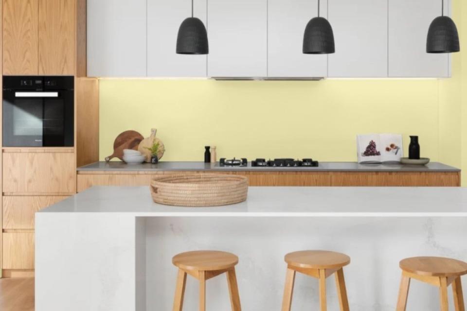 Kitchen with white island, light wood barstools, and walls painted in Golden Straw paint.