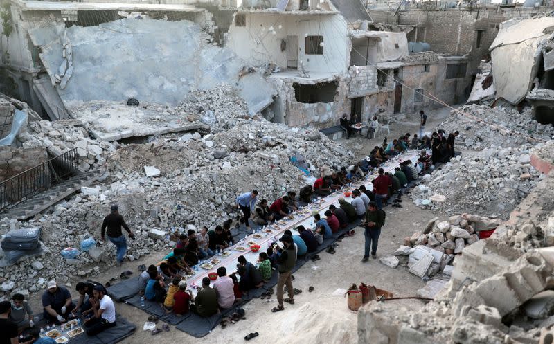 People eat their Iftar meal provided by a group of volunteers in a damaged neighbourhood, amid fear for the coronavirus disease (COVID-19) outbreak, in Atarib