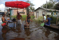 Residents cook on a street flooded by the rise of the Negro river in Iranduba, Amazonas state, Brazil, Monday, May 23, 2022. The Amazon region is being hit hard by flooding with 35 municipalities that are facing one of their worst floods in years and the water level is expected to rise over the coming months. (AP Photo/Edmar Barros)