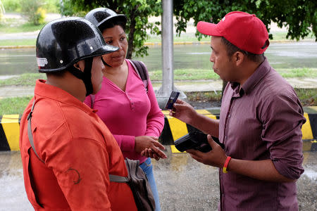 A worker explains Venezuela's new digital fuel payment system to motorists at a gas station of the Venezuelan state-owned oil company PDVSA in Caracas, Venezuela September 24, 2018. REUTERS/Marco Bello