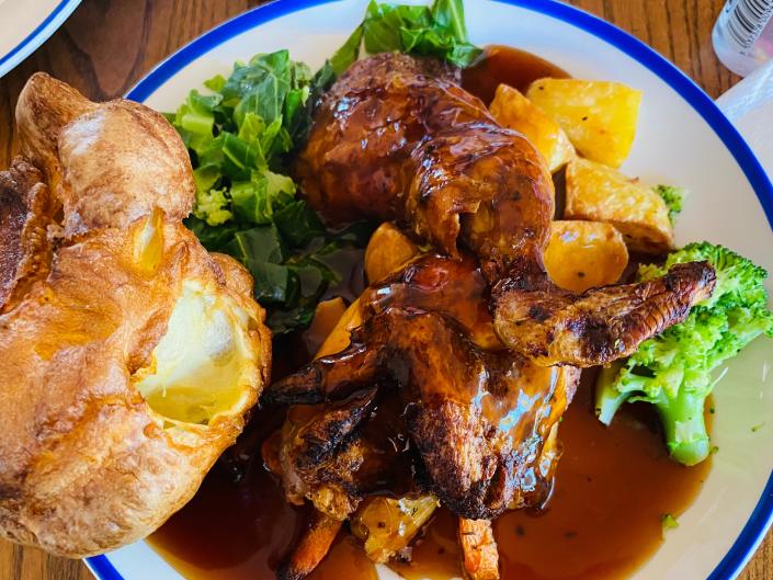 a sunday roast in the uk - a potato, gravy, meat, broccoli on a plate