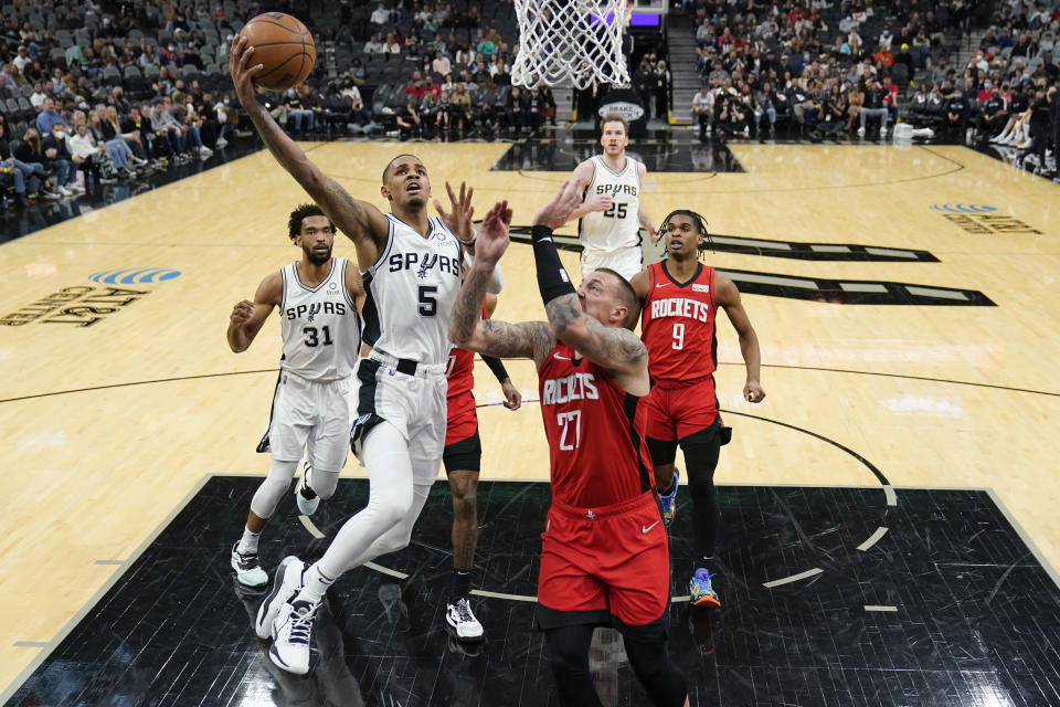 San Antonio Spurs guard Dejounte Murray (5) drives to the basket past Houston Rockets center Daniel Theis (27) during the second half of an NBA basketball game, Wednesday, Jan. 12, 2022, in San Antonio. (AP Photo/Eric Gay)