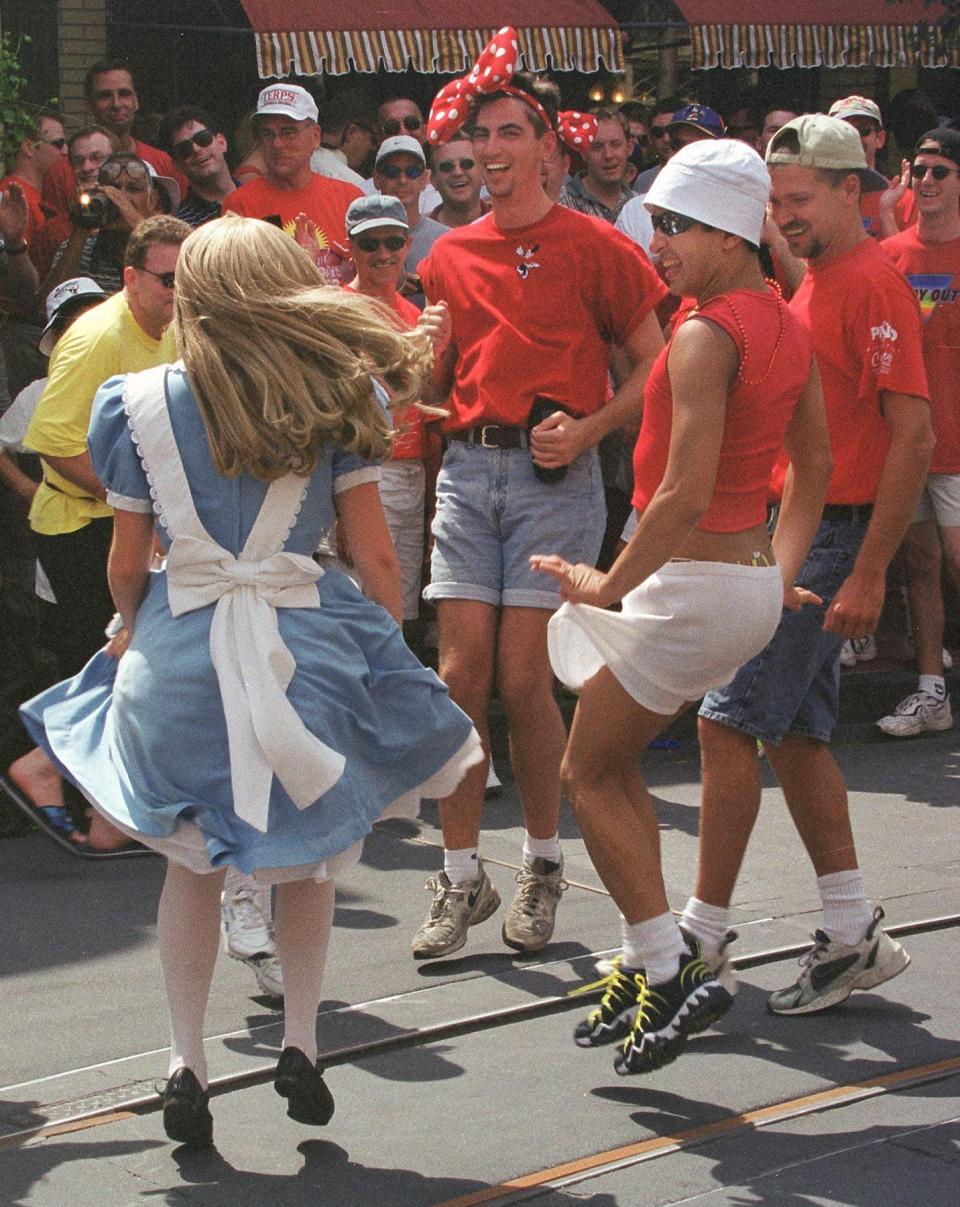 A group of Gay Days visitors dance with an Alice character in June 1999.