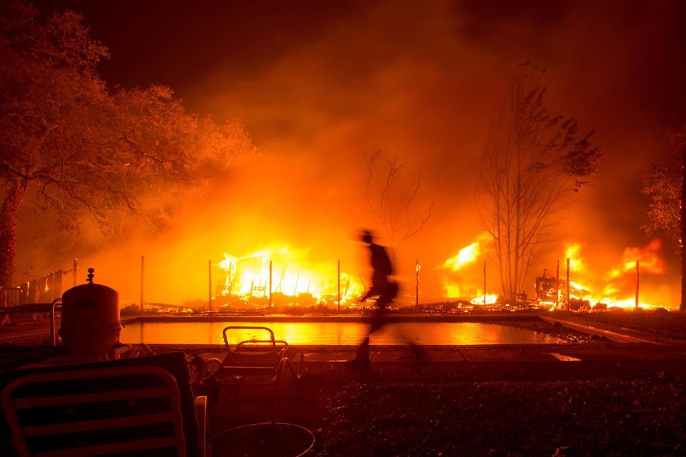 A firefighter walks near a pool as a neighboring home burns in the Napa wine region of California on Oct. 9, 2017.