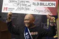 Cheng "Charlie" Saephan holds a check above his head after speaking during a news conference where it was revealed that he was one of the winners of the $1.3 billion Powerball jackpot at the Oregon Lottery headquarters on Monday, April 29, 2024, in Salem, Ore. (AP Photo/Jenny Kane)