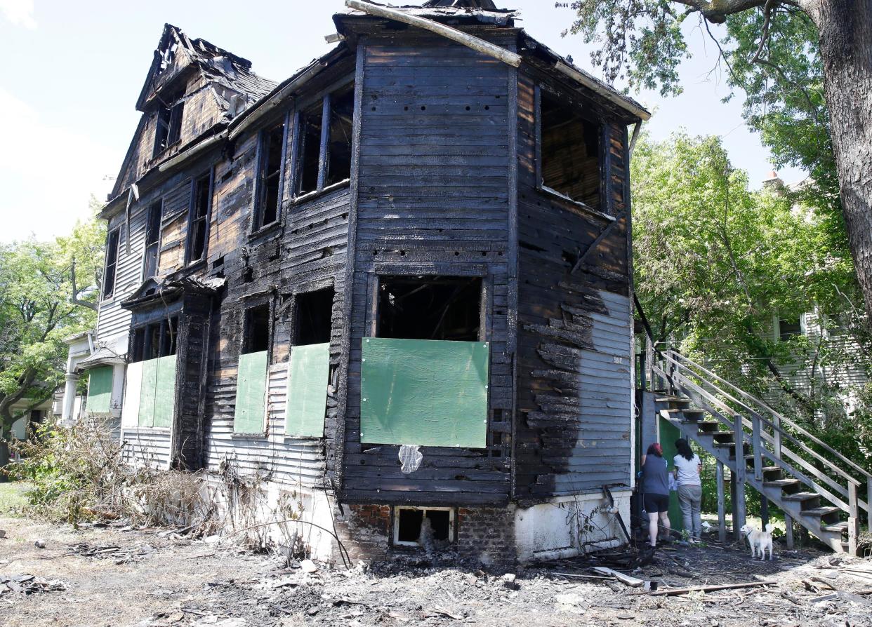 Neighbors collect remnants from outside a home that was burned this week during civil unrest. Jaleesa Hall lived in the house on North 40th Street that got burned. At the time, she was away giving birth to a daughter at the hospital.