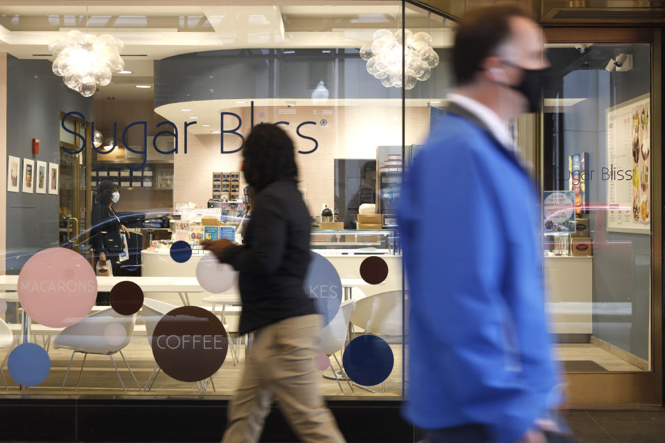 People walk past Sugar Bliss Bakery in Chicago's famed Loop on Tuesday, May 4, 2021. In many downtown areas where companies closed their offices and commuting ground to a halt, sandwich shops, bakeries and other small businesses are waiting with guarded optimism for their customers to return. (AP Photo/Shafkat Anowar)