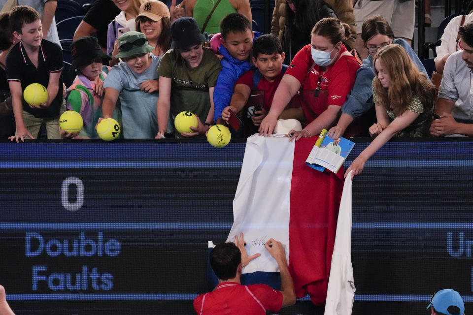 Daniil Medvedev of Russia autographs a Russian flag after defeating Marcos Giron of the U.S. in their first round match at the Australian Open tennis championship in Melbourne, Australia, Monday, Jan. 16, 2023. (AP Photo/Aaron Favila)