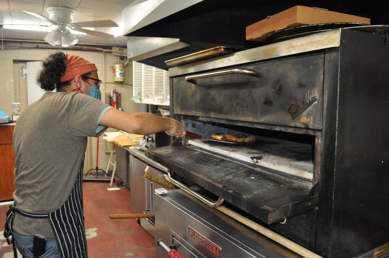 Joel Cosme checks on a pizza baking in an oven at Off Center Patio and Pub, 5286 Center St. in Hilliard.