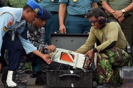 The flight data recorder of AirAsia QZ8501 is lifted out of a carrying case at the airbase in Pangkalan Bun, Central Kalimantan January 12, 2015. REUTERS/Adek Berry/Pool