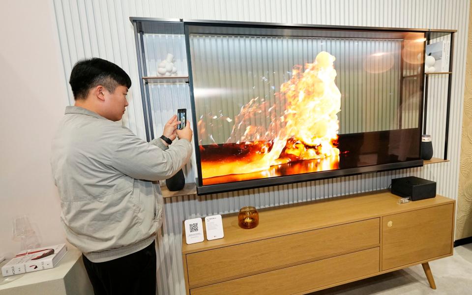 A show attendee sneaks a peek behind the world's first transparent TV made by LG