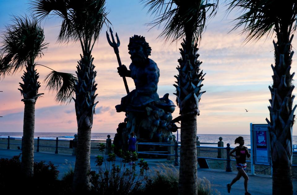 The bronze statue of Neptune stands with the sunrise behind, Wednesday, September 12, 2018, in Virginia Beach, Virginia.