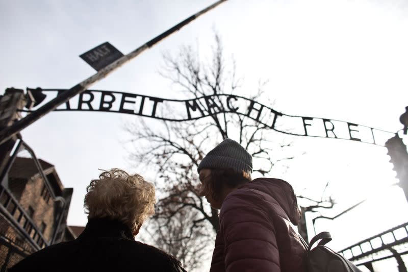 Jona Laks, survivor of Dr. Josef Mengele's twins experimentsand her granddaughter, Lee Aldar stand next to the gate with the slogan "Arbeit macht frei" ("Work sets you free") as they start their visit at the Auschwitz death camp in Oswiecim