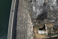 A car passes the dam of Marathon Lake, over a blackened forest which had been burned in a mid-August wildfire, about 36 kilometres (22 miles) north of Athens, Thursday, Aug. 22, 2024. (AP Photo/Thanassis Stavrakis)