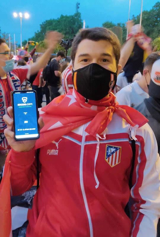 Fan of Spain's Atletico Madrid poses for a picture as he holds a phone with Chiliz's Socios.com app, in Madrid