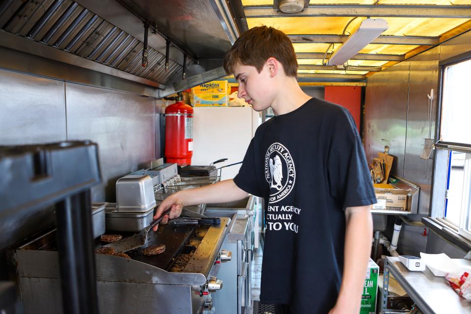Ryan Benning, 14, grills hamburgers for customers in the Hangover Hut food truck in Harrisburg, South Dakota, on Thursday, June 2.