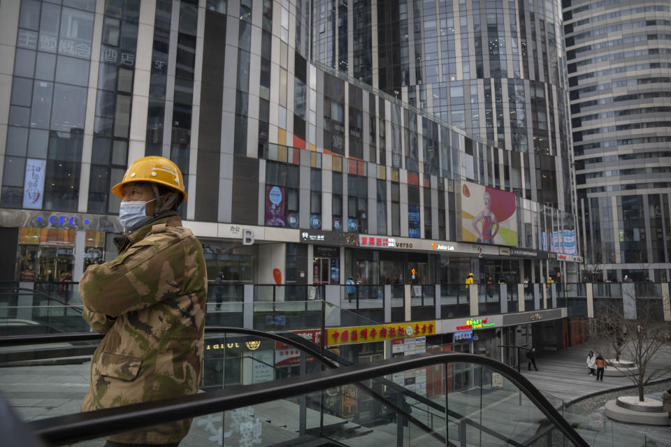 A worker wearing a face mask rides an escalator at a shopping and office complex in Beijing, Wednesday, Jan. 11, 2023. Japan and South Korea on Wednesday defended their border restrictions on travelers from China, with Tokyo criticizing China's move to suspend issuing new visas in both countries as a step unrelated to virus measures. (AP Photo/Mark Schiefelbein)