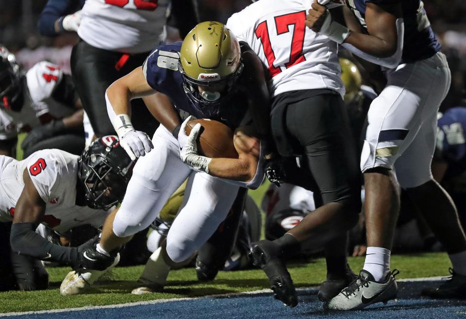 Hoban running back Brayton Feister is tripped by Glenville defensive back Jermaine Agee, left, as he scores a touchdown during the first half of a high school football game, Friday, Oct. 6, 2023, in Akron, Ohio.