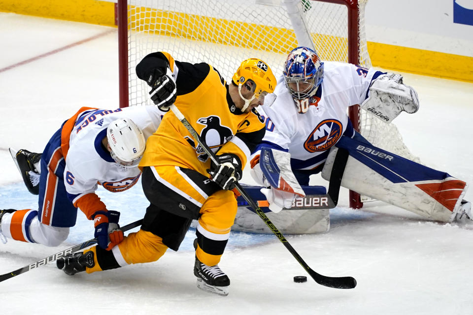 Pittsburgh Penguins' Sidney Crosby, center, cannot get his stick on the puck in front of New York Islanders goaltender Ilya Sorokinin, right, with Islanders' Ryan Pulock (6) defending during the first period of Game 1 of an NHL hockey Stanley Cup first-round playoff series in Pittsburgh, Sunday, May 16, 2021. (AP Photo/Gene J. Puskar)