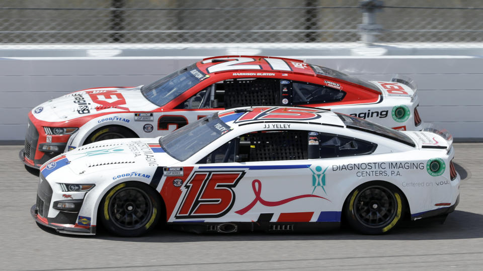 Harrison Burton (21) and J.J.Yeley (15) race side-by-side while coming out of Turn 4 during a NASCAR Cup Series auto race at Kansas Speedway in Kansas City, Kan., Sunday, May 15, 2022. (AP Photo/Colin E. Braley)