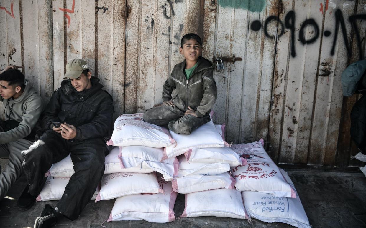 Palestinians await the distribution of UNRWA flour. <a href="https://www.gettyimages.com/detail/news-photo/palestinians-who-left-their-homes-and-took-refuge-in-rafah-news-photo/1899261787?adppopup=true" rel="nofollow noopener" target="_blank" data-ylk="slk:Abed Zagout/Anadolu via Getty Images;elm:context_link;itc:0;sec:content-canvas" class="link ">Abed Zagout/Anadolu via Getty Images</a>