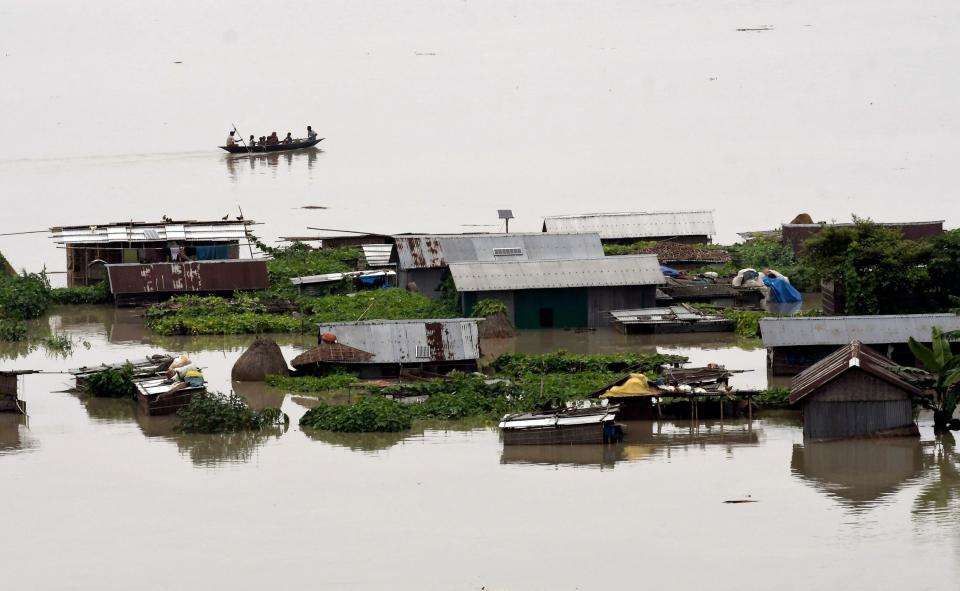 Villagers cross flood waters in their submerged village in the flood affected Morigaon district of Assam, India (EPA/STR)