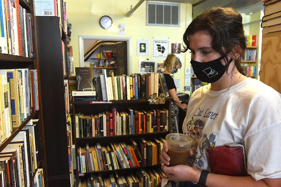 Bailey Martin, a junior at the University of Missouri, browses books while wearing a mask at the Yellow Dog Bookshop.