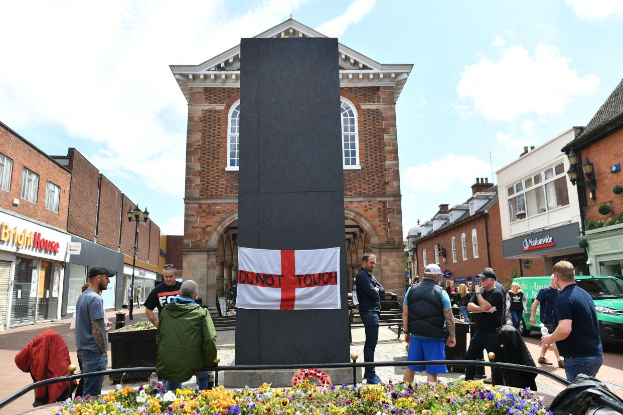 A group of men stand beside the boarded up statue of Sir Robert Peel in Tamworth on Saturday. (PA)