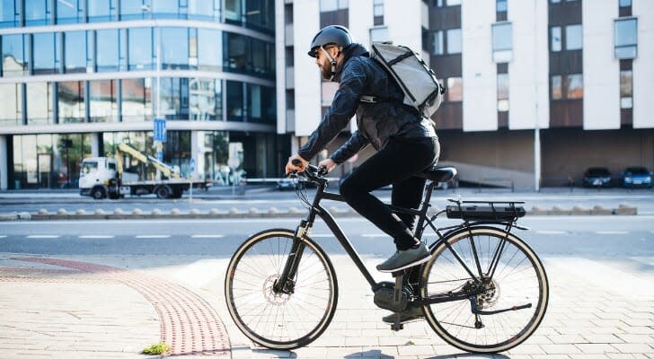 A bicyclist wearing a helmet rides on a city street. SmartAsset analyzed various data sources to identify the most bike-friendly cities in the U.S. 