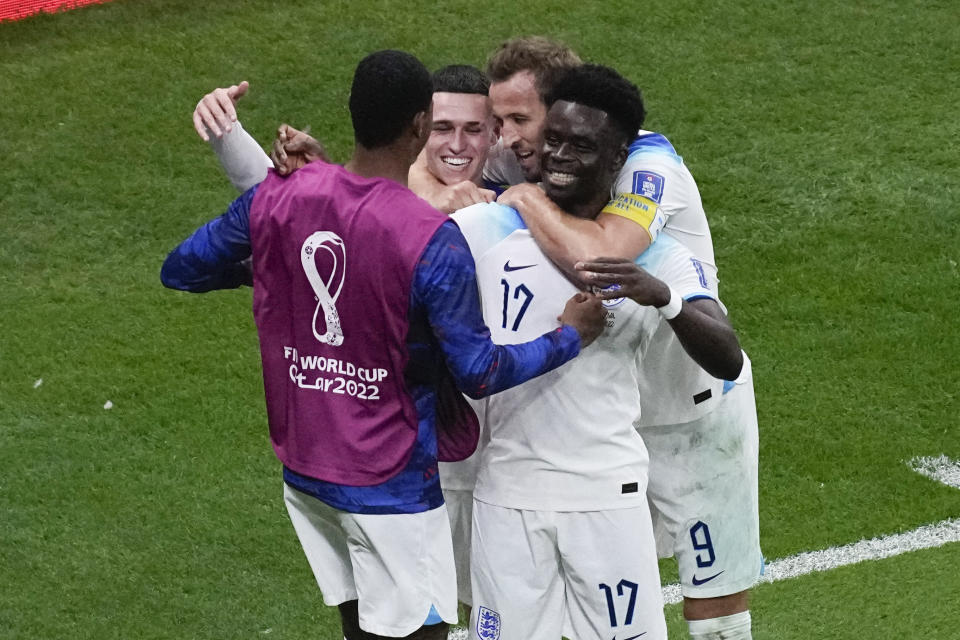 England's Bukayo Saka, right, celebrates with teammates after scoring during the World Cup round of 16 soccer match between England and Senegal, at the Al Bayt Stadium in Al Khor, Qatar, Sunday, Dec. 4, 2022. (AP Photo/Darko Bandic)