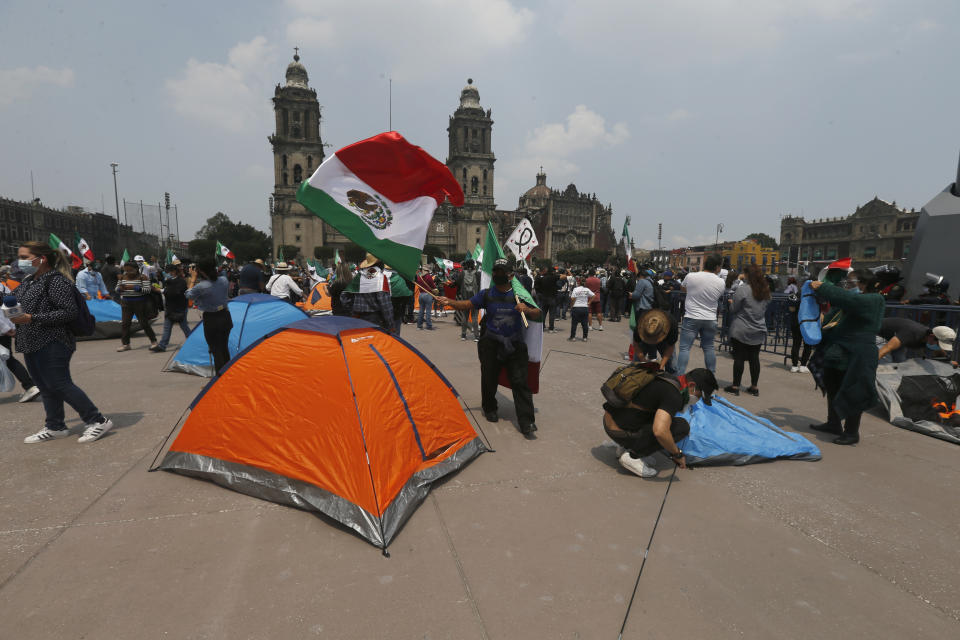 Demonstrators who are demanding the resignation of Mexican President Andrés Manuel López Obrador, commonly known by his initials AMLO, break into Mexico City's main square the Zocalo, Wednesday, Sept. 23, 2020. After being blocked from entering the plaza for several days by the police the demonstrators were able to jump past police barricades and install themselves there. (AP Photo/Marco Ugarte)