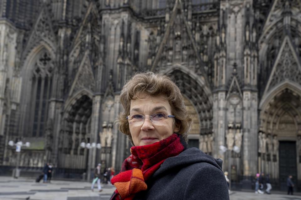 Regina Oediger-Spinrath, spokeswoman for the professional association of pastoral assistants in the Cologne archdiocese, poses for a portrait in front of the Cologne Cathedral in Cologne, Germany, Wednesday, Nov. 30, 2022. An unprecedented crisis of confidence is shaking the Archdiocese of Cologne. Catholic believers have protested their deeply divisive bishop and are leaving in droves over allegations that he may have covered up clergy sexual abuse reports. (AP Photo/Michael Probst)