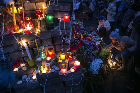 A woman lights a candle to pay her respects to fallen anti-Yanukovich protesters in Kiev's Independence Square in this February 23, 2014 file photo. REUTERS/Baz Ratner/Files