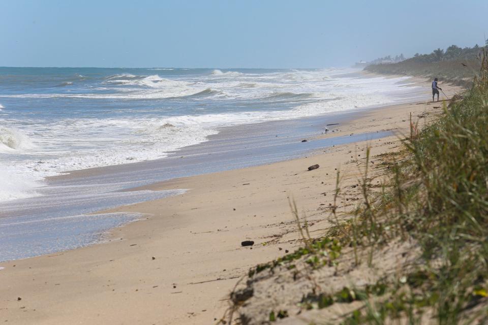 A person walks the beach with a metal detector near the Ambersands Beach Access on Friday, Sept. 30, 2022, a day after Hurricane Ian impacted the Treasure Coast with strong winds, rain and beach erosion. 