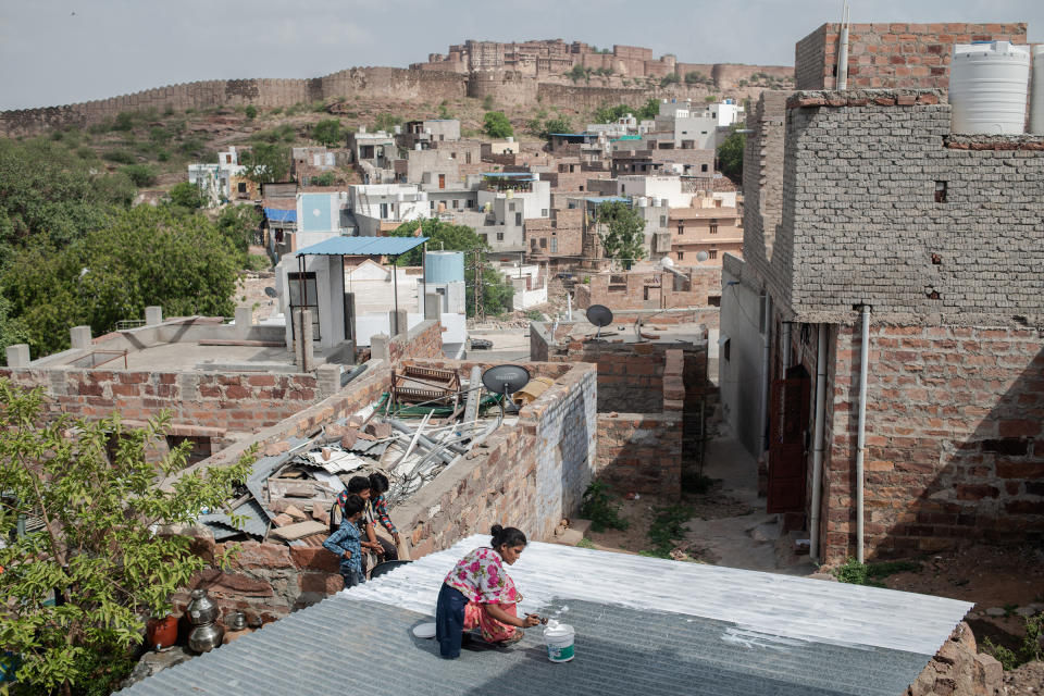 Resident Nandini Chohan, 16, paints the roof of the home she shares with her family with reflective paint following an assessment by the Mahila Housing Trust in Chandpole on June 14 in Jodhpur, India. The Mahila Housing Trust trains women to work in their communities to assess and implement measures to mitigate the impact and effects of climate change and rising temperatures, including how to keep their homes cool.<span class="copyright">Rebecca Conway—Getty Images</span>