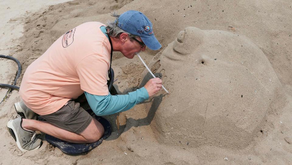 Bob May, of St. Cloud, Michigan uses a straw to create a design for his sculpture during the Wisconsin Sand Sculpting Festival at Red Arrow Park and Beach, Friday, July 14, 2023, in Manitowoc, Wis.