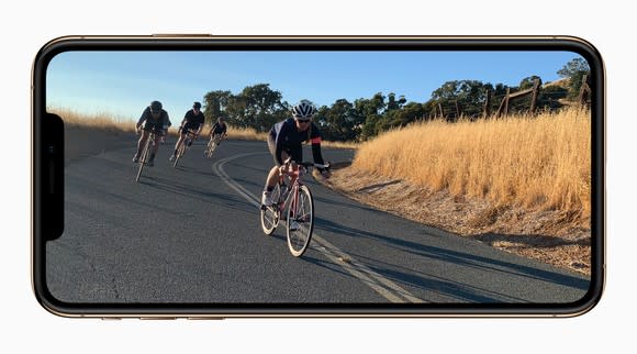 iPhone XS Max with a photo of people riding bikes displayed.