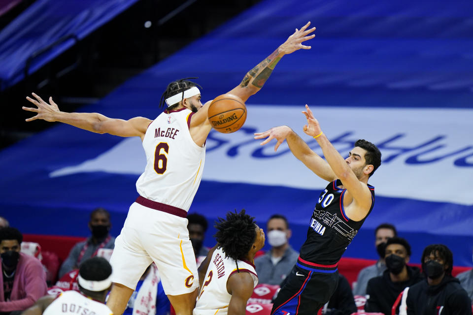 Philadelphia 76ers' Furkan Korkmaz, right, passes the ball against Cleveland Cavaliers' JaVale McGee during the first half of an NBA basketball game, Saturday, Feb. 27, 2021, in Philadelphia. (AP Photo/Matt Slocum)