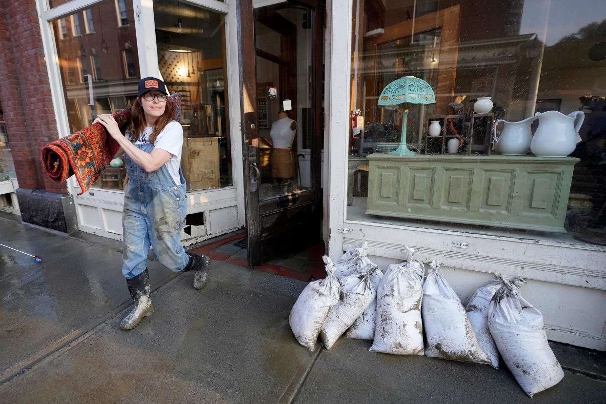 Juliana Jennings, of Montpelier, Vt., removes a wet Persian rug from the flood-damaged antique, art, and furnishing store J. Langdon she shares with her husband, in downtown Montpelier, Vermont (AP)