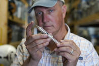 Movie prop master Scott Reeder displays a retractable stunt syringe and needle at his shop in Austin, Texas, on April 26, 2021. Reeder's TikTok video about prop retractable needles was used without his permission to spread false claims about politicians getting fake vaccinations. Individuals across the country, like Reeder, have found themselves swept into the misinformation maelstrom, their online posts or their very identities hijacked by anti-vaccine activists and others peddling lies about the COVID-19 outbreak. (AP Photo/Eric Gay)