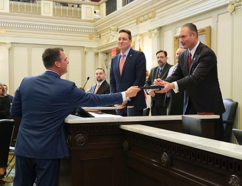 Gov. Stitt hands House Speaker Charles McCall a folder Monday during the start of the Legislature and Stitt's State of the State speech to the joint session.