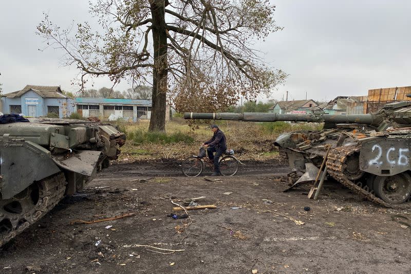 Un residente local pasa en bicicleta al lado de tanques rusos abandonados en Kurylivka, en Járkov