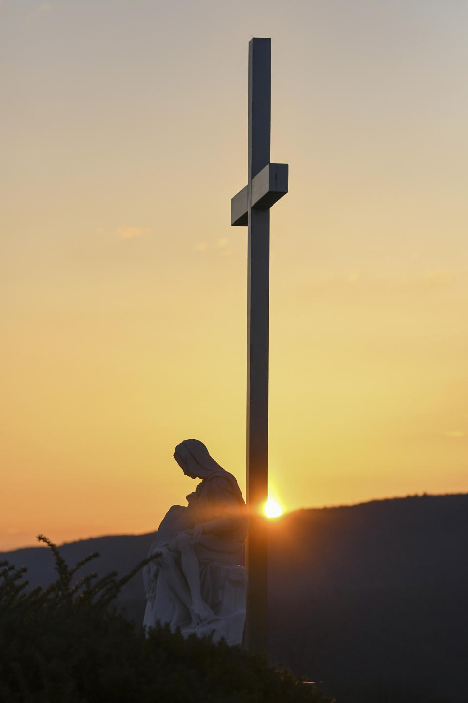 FILE - The Pieta statue is seen as the sun rises during St. Patrick Roman Catholic Church's annual Easter Sunday service at sunrise at Our Lady of Calvary Cemetery in Pottsville, Pa., on Sunday, April 17, 2022. On Easter morning, many Christians wake before dawn. They will celebrate their belief in the resurrection of Jesus, the son of God, as the sun rises. (Jacqueline Dormer/Republican-Herald via AP, File)