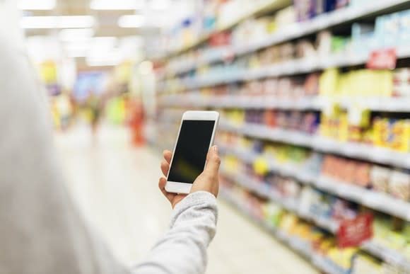 A man checks his smartphone while shopping.