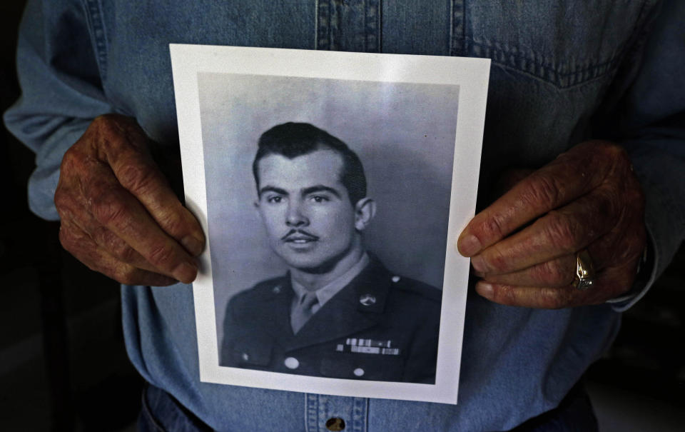 FILE - In this April 17, 2014 file photo, Ray Lambert, a 1st Infantry Division combat veteran of the D-Day invasion, holds a copy of an old photograph of himself in uniform at his home in Seven Lakes, N.C. Ray Lambert, the Army medic who survived multiple wounds on D-Day and was saluted by a president on the World War II battle's 75th anniversary, died on Friday, April 9, 2021. He was 100. (AP Photo/Gerry Broome, File)