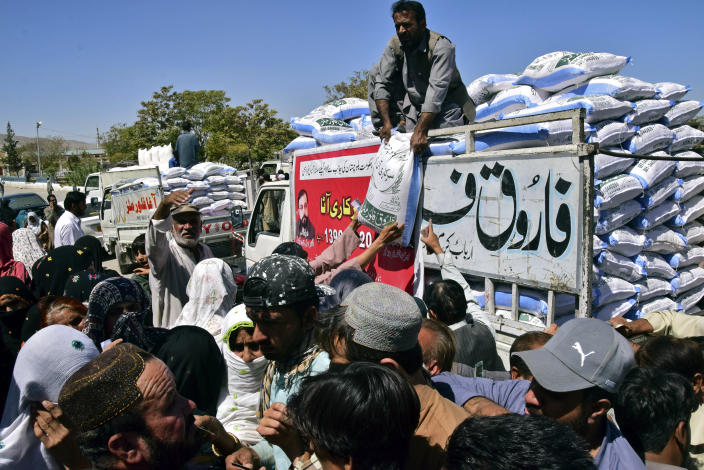 Flood victims jostle to buy flour in Quetta, Pakistan, Wednesday, Sept. 21, 2022. Devastating floods in Pakistan's worst-hit province have killed 10 more people in the past day, including four children, officials said Wednesday as the U.N. children's agency renewed its appeal for $39 million to help the most vulnerable flood victims. (AP Photo/Arshad Butt)