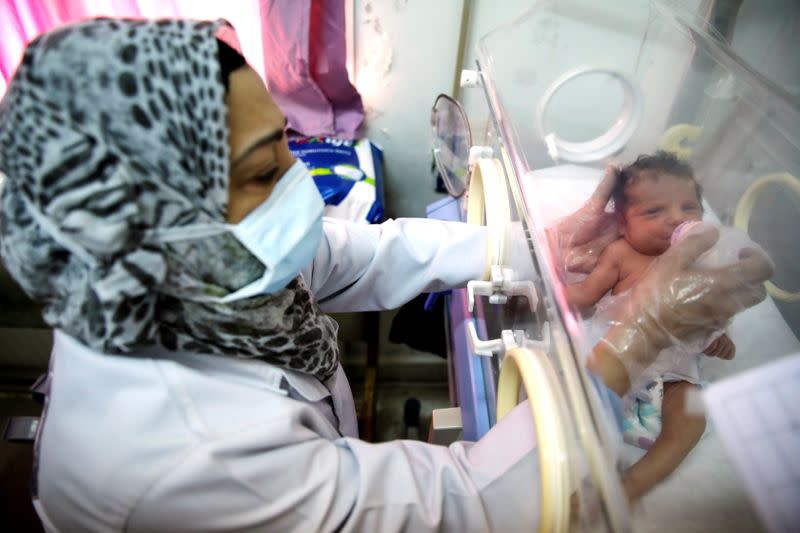 A nurse bottle feeds a premature baby at a maternity hospital in Idlib