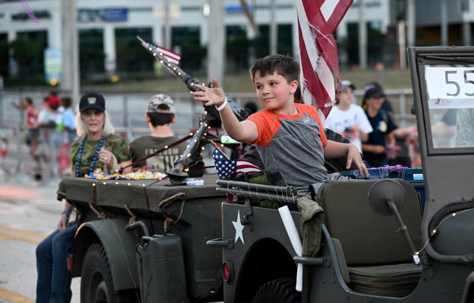 A boy on one of the military jeeps throws beads to the crowds during the DeSoto Parade on Saturday, April 27, 2024.