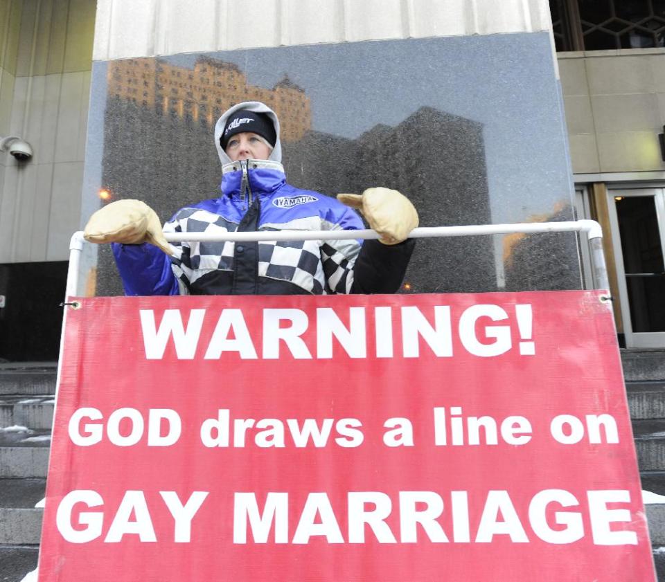 Christine Weick of Hopkins, Mich., protests outside Federal Courthouse before a trial that could overturn Michigan's ban on gay marriage in Detroit on Monday, March 3, 2014 in Detroit. Lisa Brown of Oakland County, the elected clerk of a Detroit-area county says she'll follow the orders of a judge when it comes to same-sex marriage, not Michigan's attorney general. Brown was asked about an email last fall from the attorney general's office, which warned county clerks not to issue marriage licenses to same-sex couples, even if a judge threw out the ban. Michigan voters banned gay marriage in 2004. In a lawsuit, Detroit-area nurses April DeBoer and Jayne Rowse say that violates the U.S. Constitution. (AP Photo/Detroit News, David Coates) DETROIT FREE PRESS OUT; HUFFINGTON POST OUT